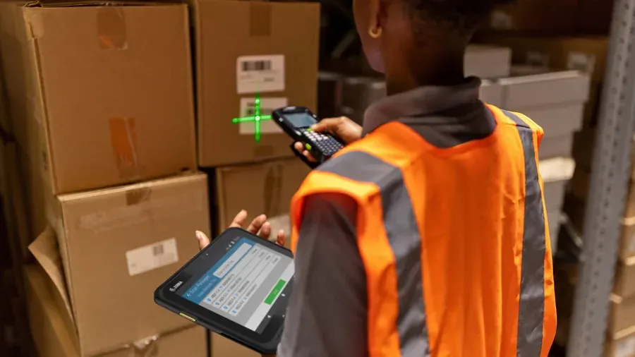 Warehouse worker scanning a box barcode while holding a tablet