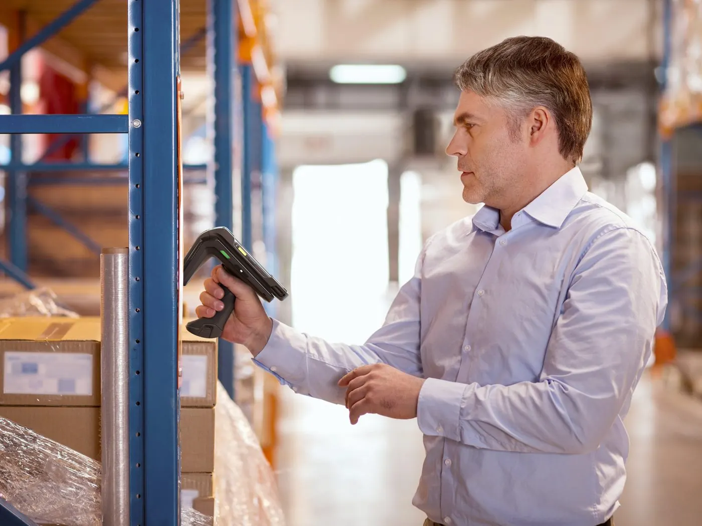 Warehouse manager scanning stock on a shelf with a handheld scanner