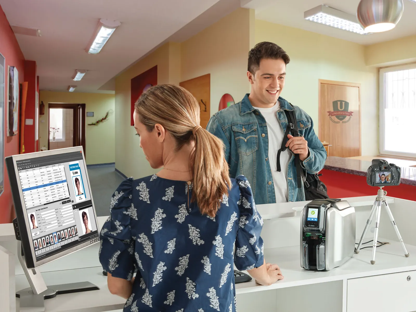 Receptionist capturing a visitor photo for an ID badge at a front desk