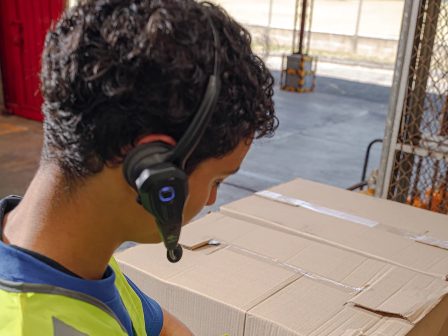 Zebra warehouse worker using a headset and wearable device at a carton